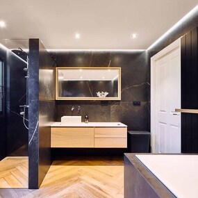 Modernes Badezimmer mit dunklen Fliesen, Holzwaschtisch, Dusche und Badewanne.