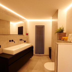 Modernes Badezimmer mit großem Spiegel, LED-Beleuchtung, Doppelwaschtisch und Handtüchern.