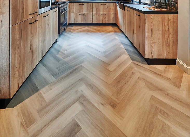 Moderne Küche mit hellen Holzfronten und Fischgrät-Vinylboden in natürlicher Optik.